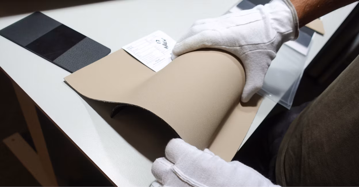 Two hands in white gloves holding a piece of leather.