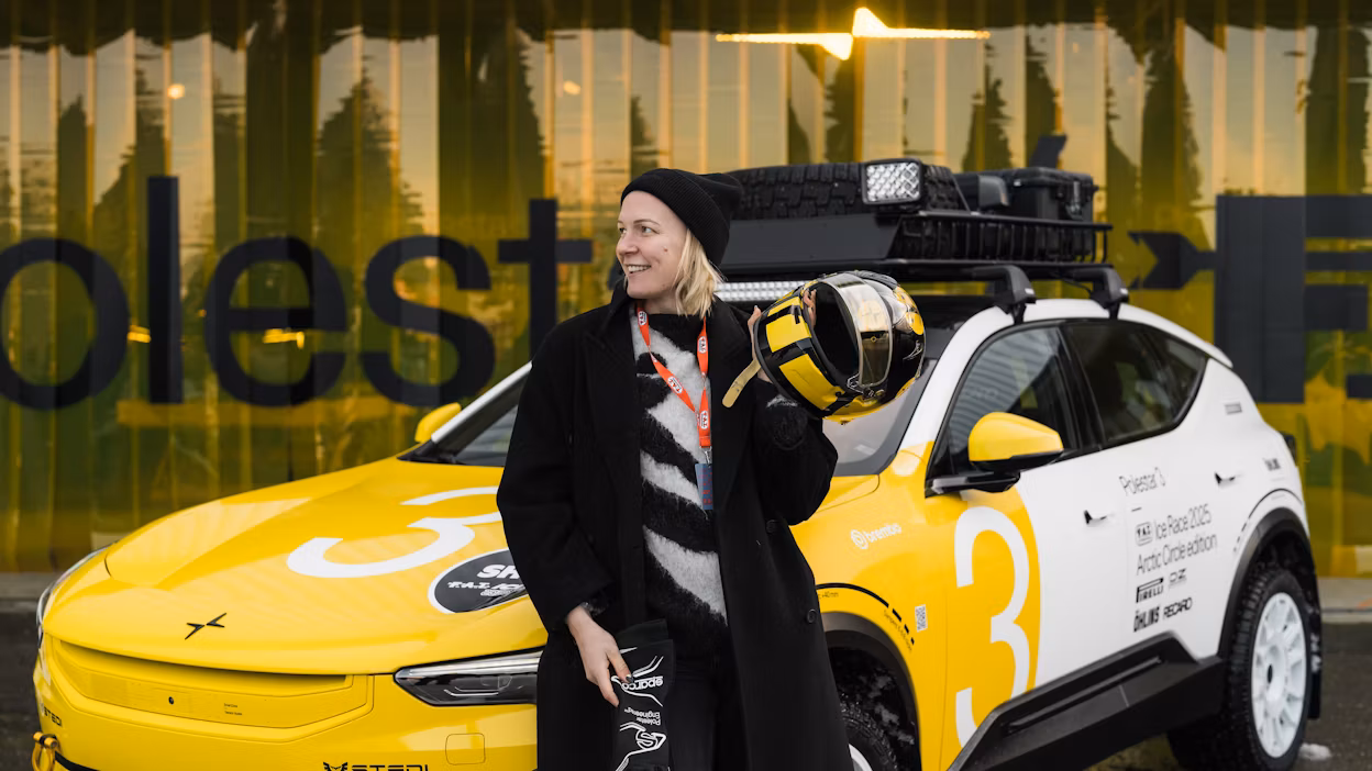 Woman sitting on Polestar 3 holding racing helmet