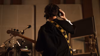 Back on man in recording studio playing guitar