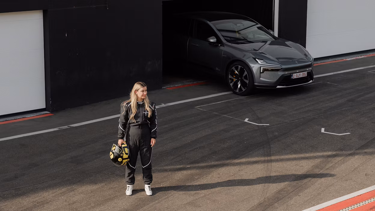 Woman in racing outfit standing in front of Polestar 4