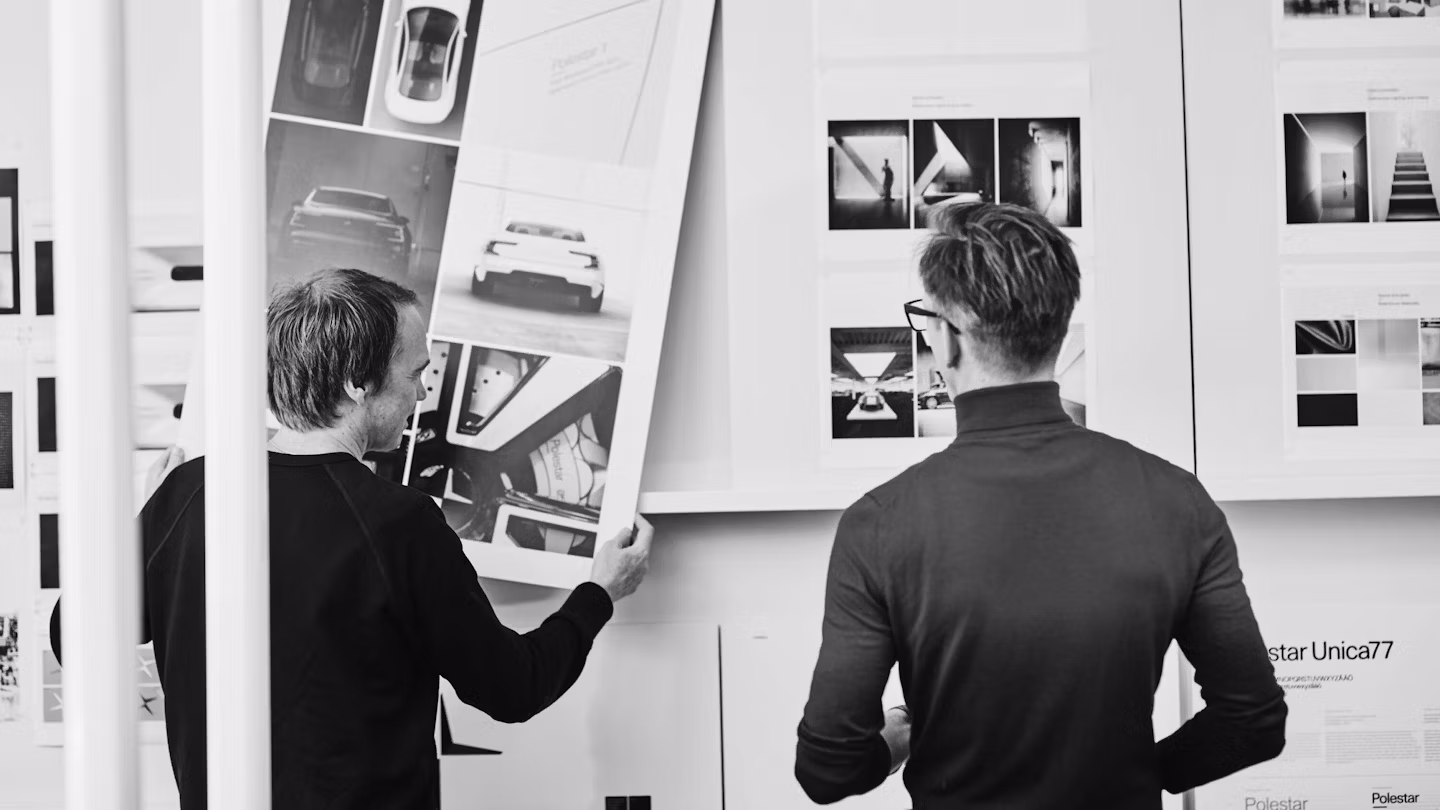 Two people, seen from behind, looking at photos on a wall