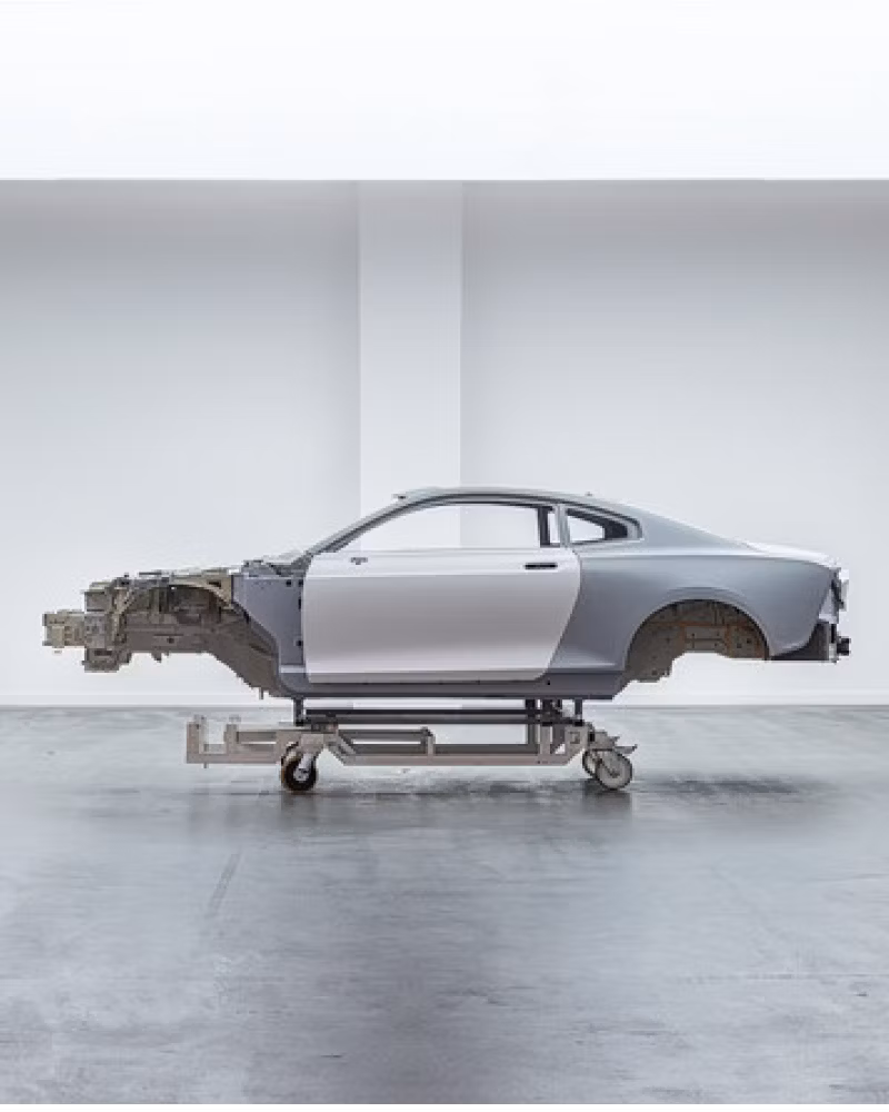 Polestar car frame on a wheeled stand in a white room.