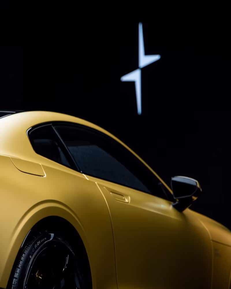 Yellow Polestar car with side mirror visible, Polestar logo in white on black background.