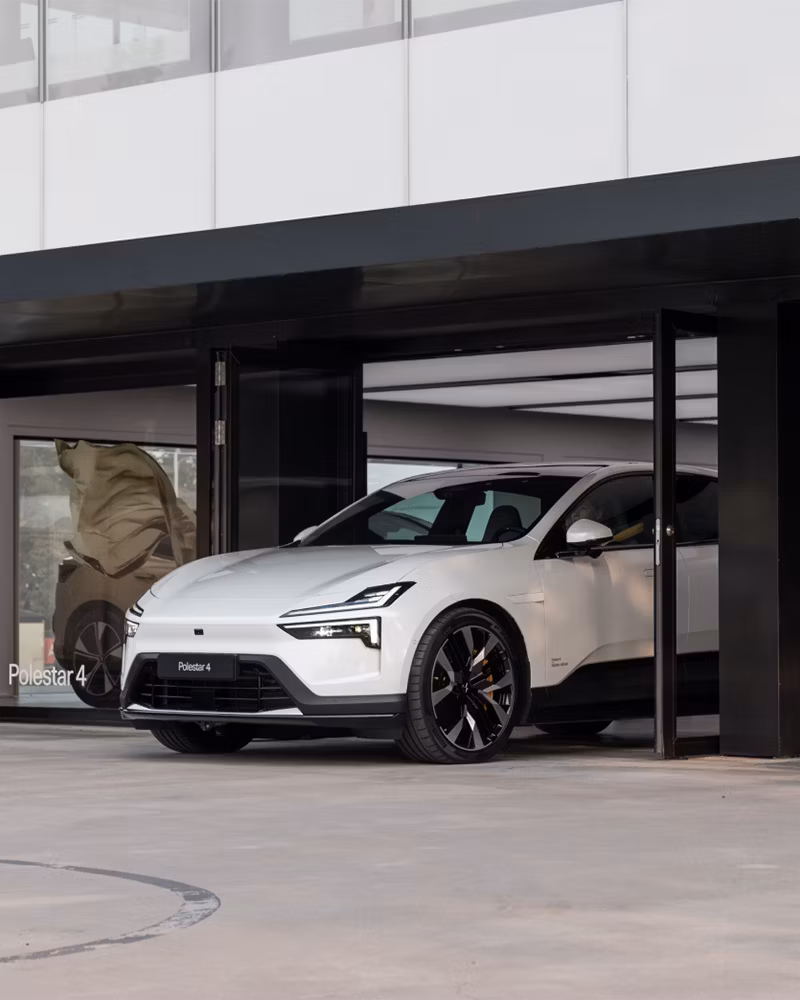 Polestar 4 car parked in front of a building with glass windows and open doors.