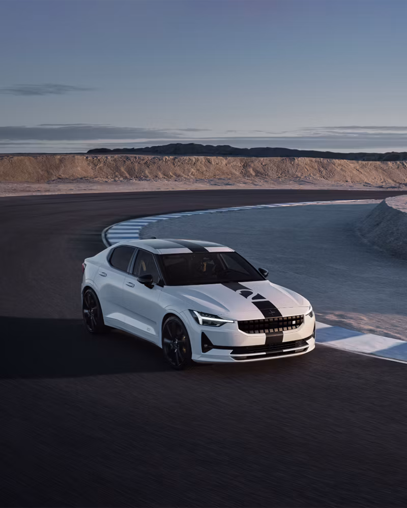 Polestar car on a curved road with desert landscape in the background under a clear sky.
